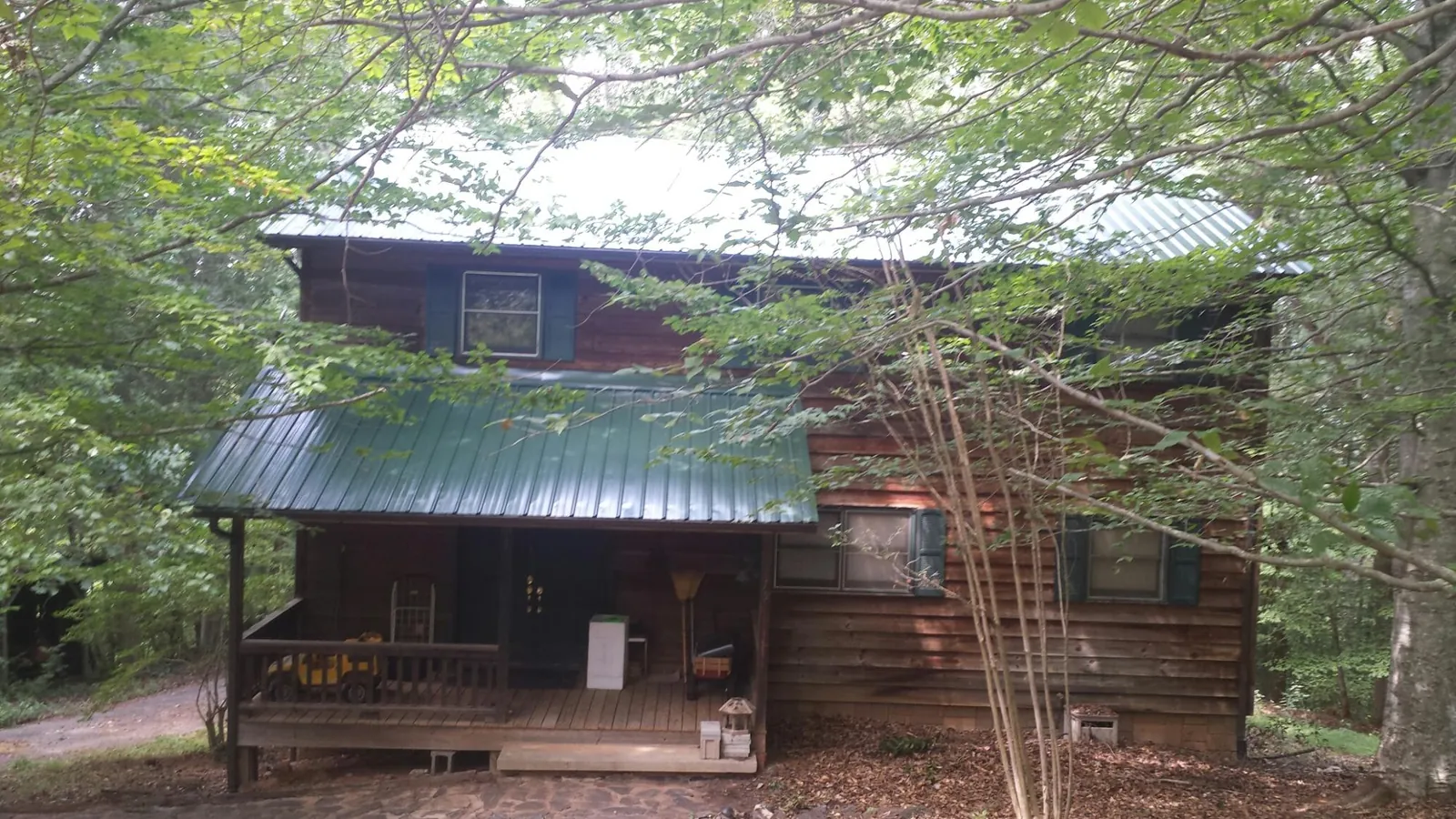 Green metal roof and covered porch on a log cabin in Andersonville