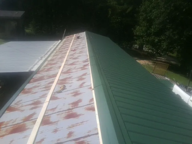 Old rusted panels beside newly installed green metal roofing — Wind Damage Roof Repair by Roofing Brothers in Andersonville