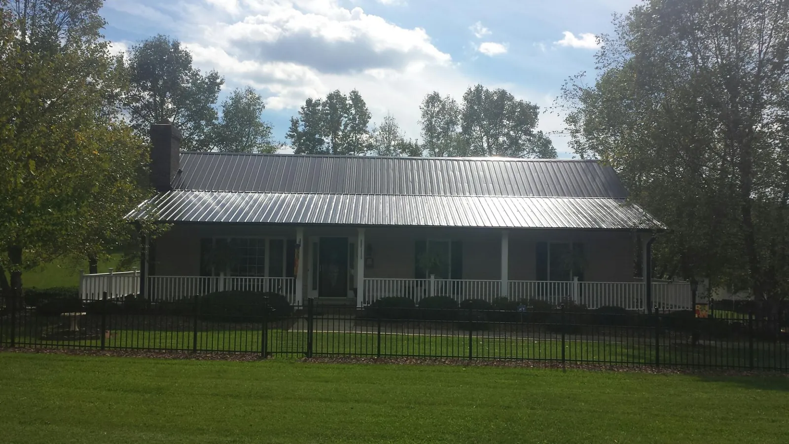 Gray metal roof on a brick ranch with a full width front porch — Gutter Guard Installation work by our crew in Andersonville