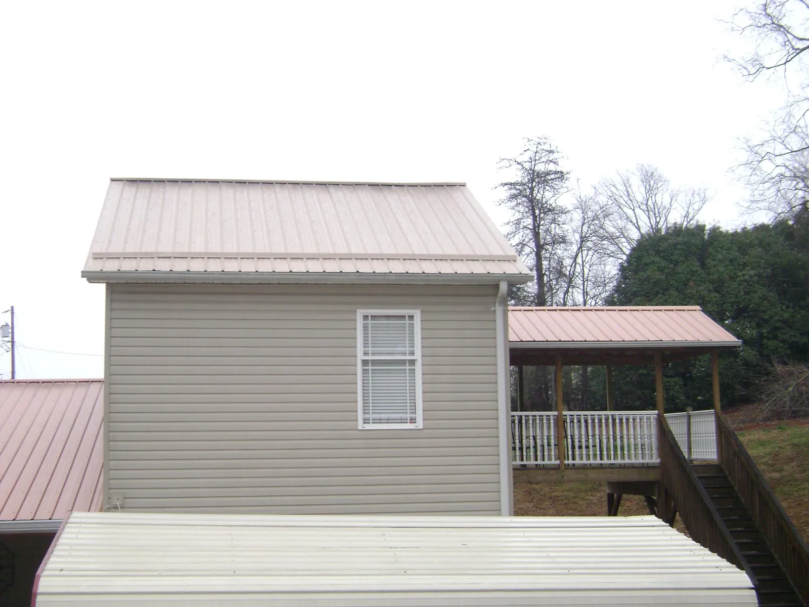 Tan metal roofs on a two story addition and attached porch, from a Roof Replacement job in Andersonville